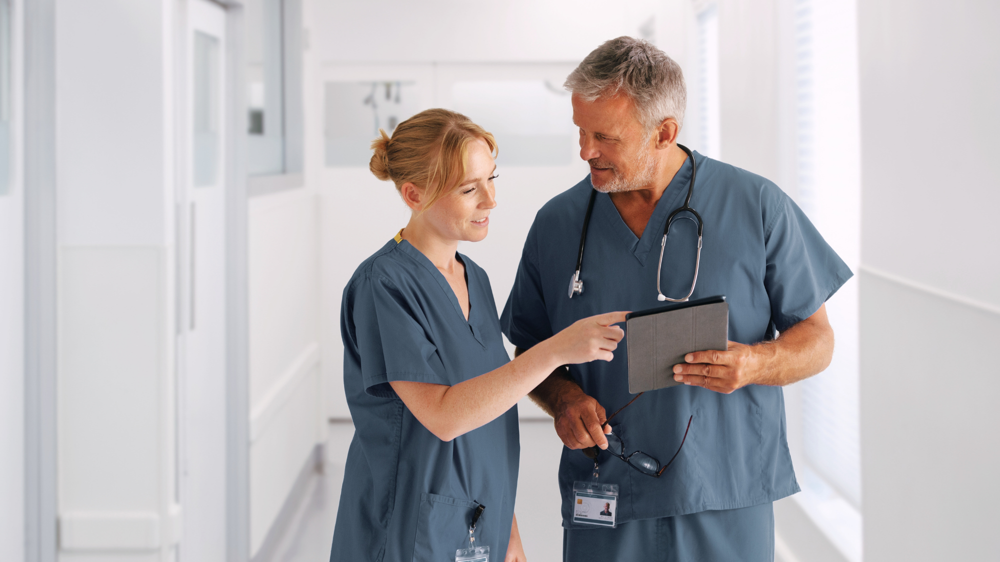 A male and female nurse conversing over a chart