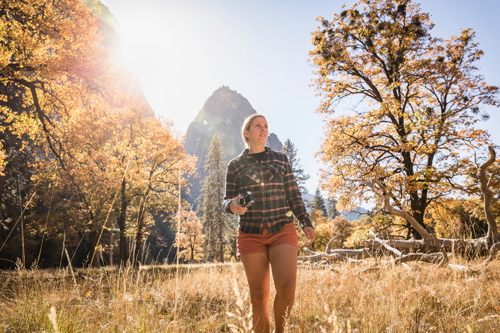 Woman with camera in autumn landscape, Yosemite National Park, California, USA