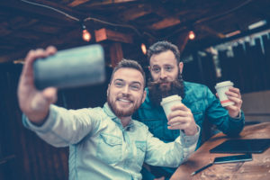 Two Bearded Friends Drinking Coffee and Taking Selfie in Restaurant