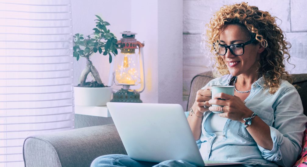 Woman on couch with coffee and laptop