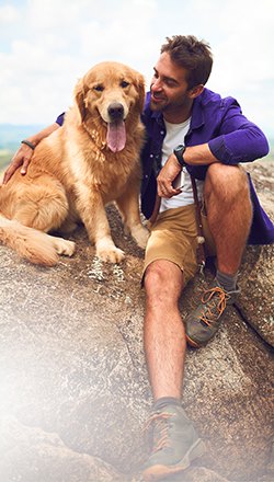 Man on rock with dog near beach