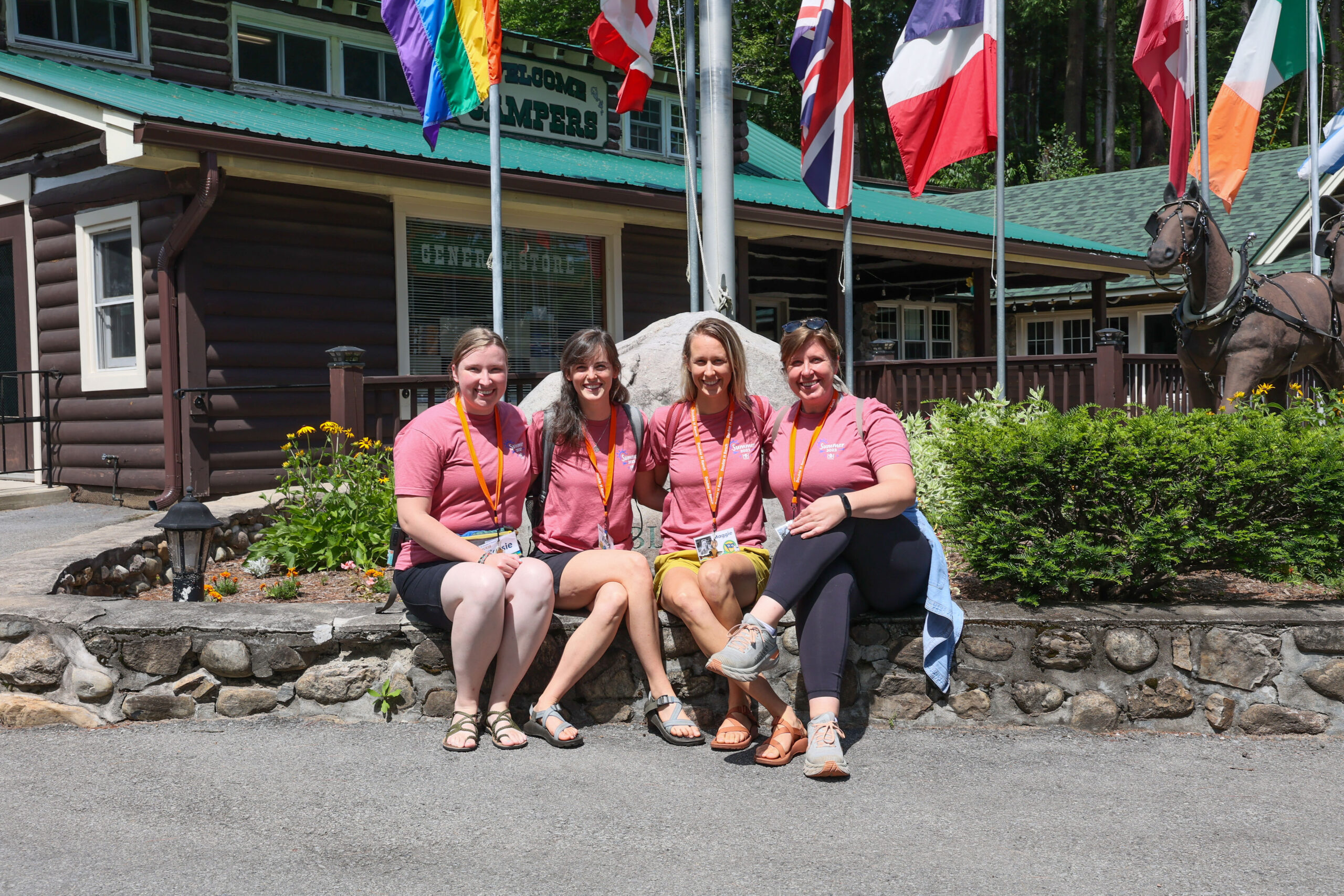 Four women in pink shirts sitting outside of summer camp