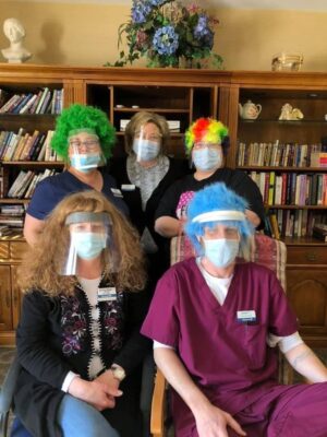 image of leigh anne with 4 other clinicians inside a library, wearing brightly colored wigs and face masks