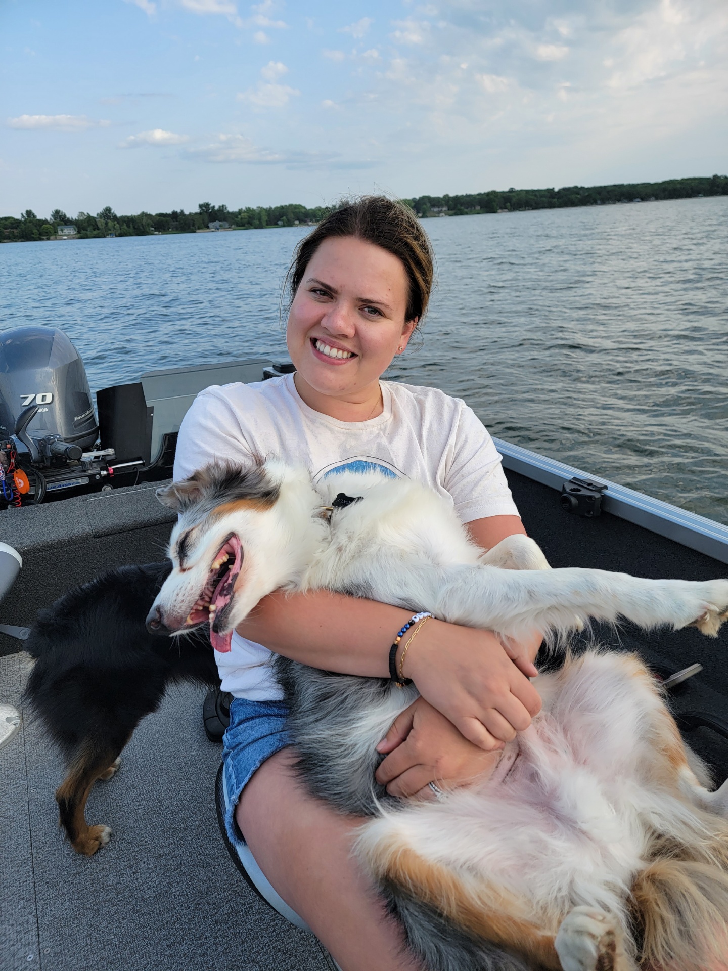 Girl holding white dog on a boat