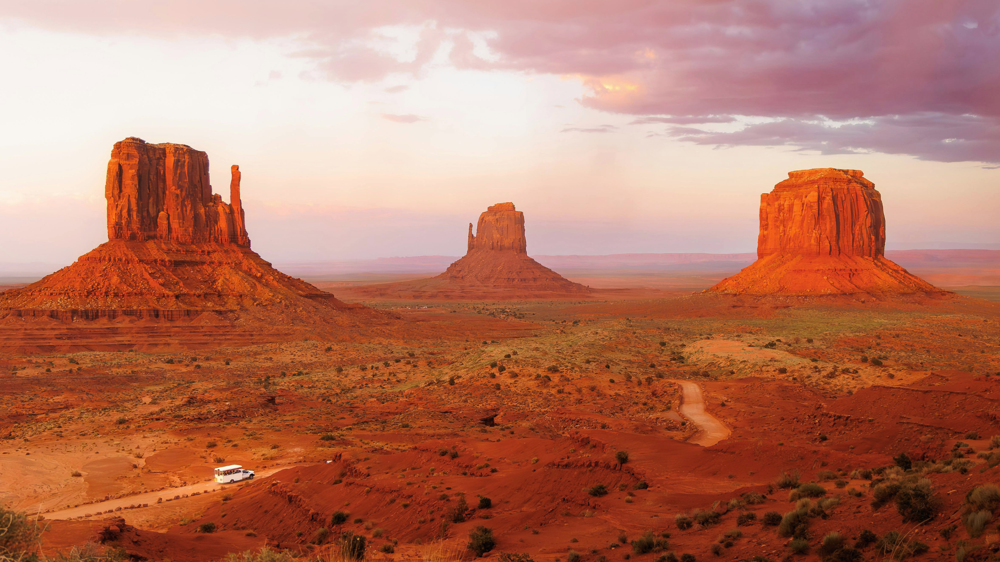 Zoomed out view of three large rock formations at the Grand Canyon at sunset.