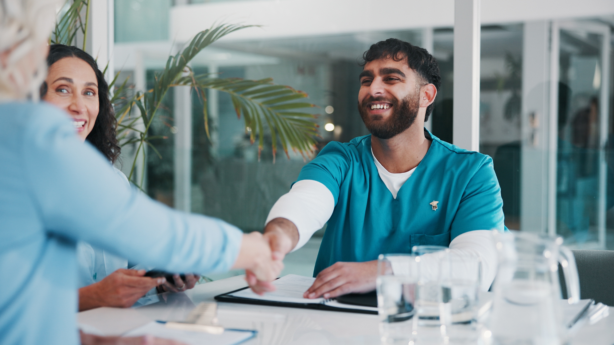 Male nurses shaking hands with a woman in a conference room.