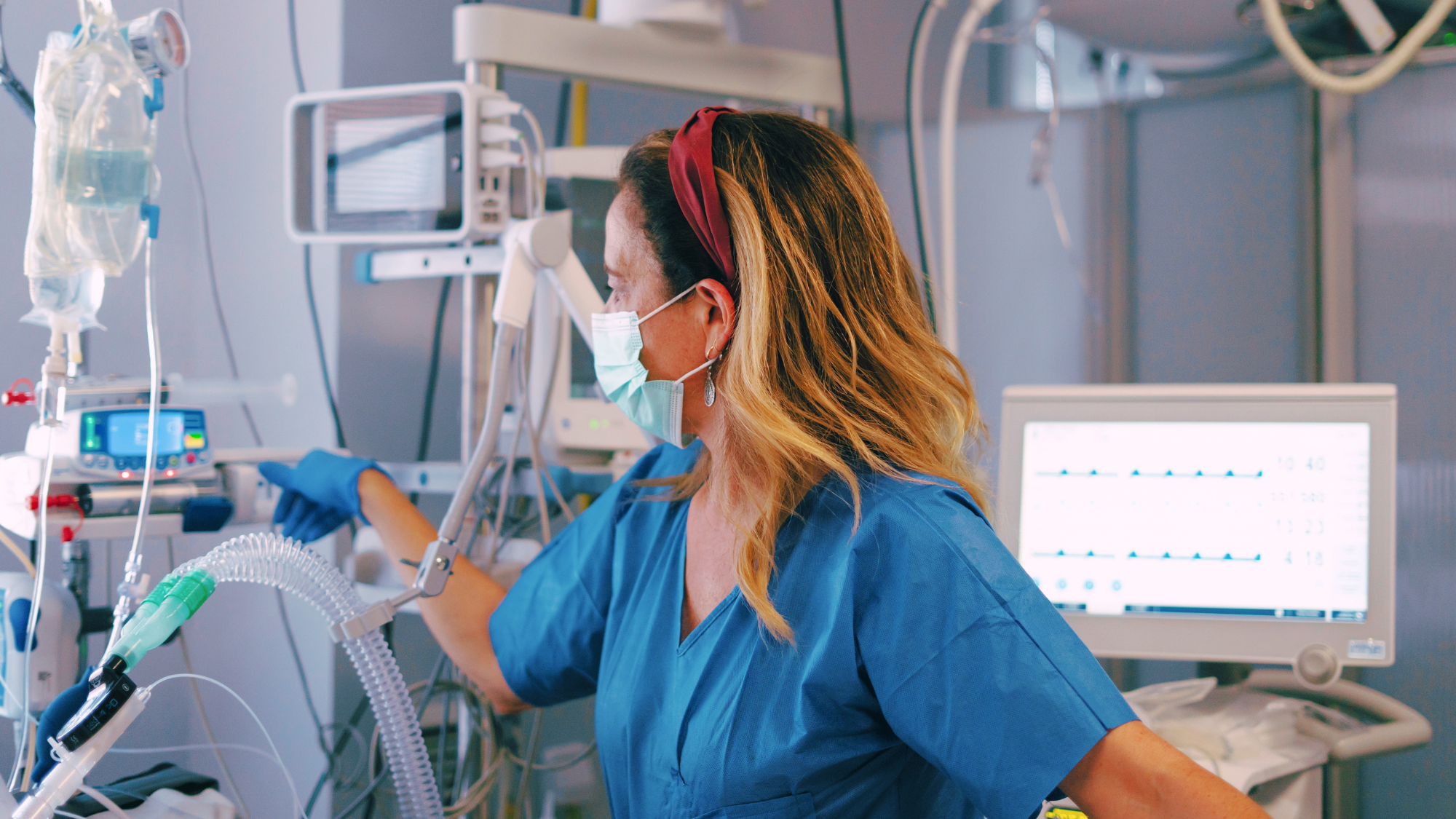 Female ICU nurse checking a patient's breathing tube.
