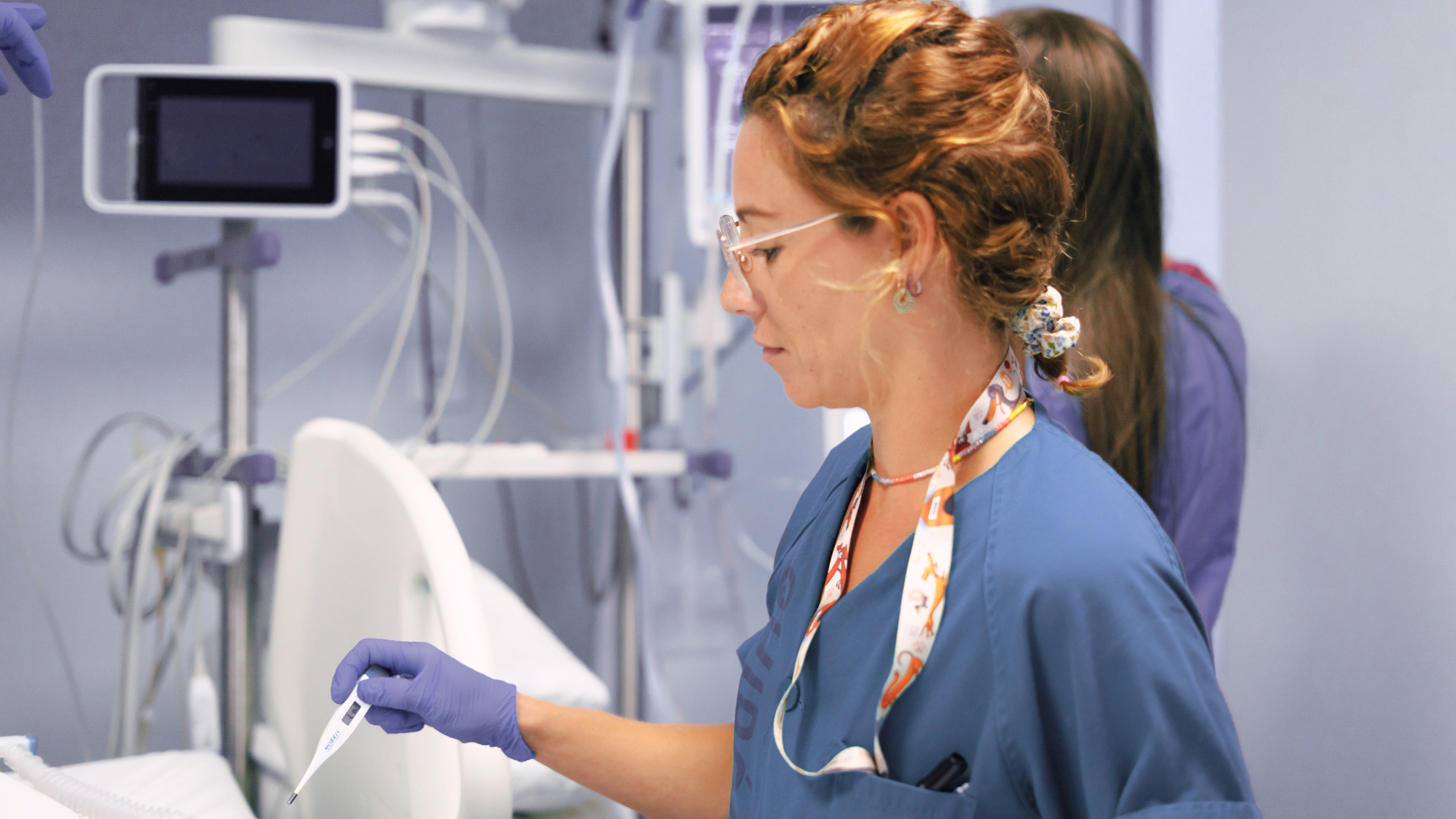 Female ICU nurse taking the temperature of a patient.