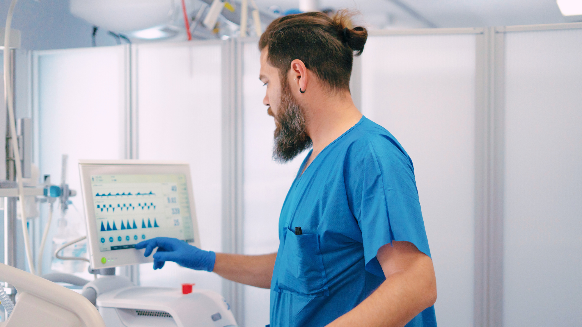 Male ICU nurse monitoring a patient's vitals.