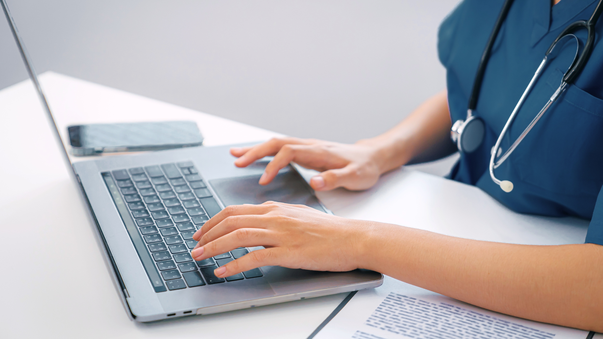 A nurses hands typing on a laptop.