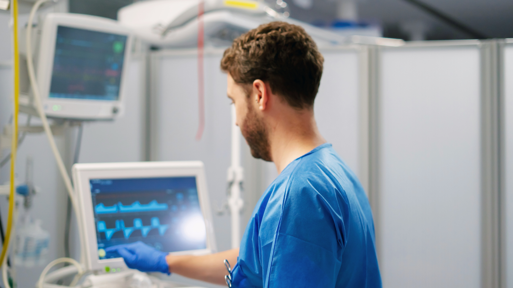Male telemetry nurse looking at a monitor in a hospital room.
