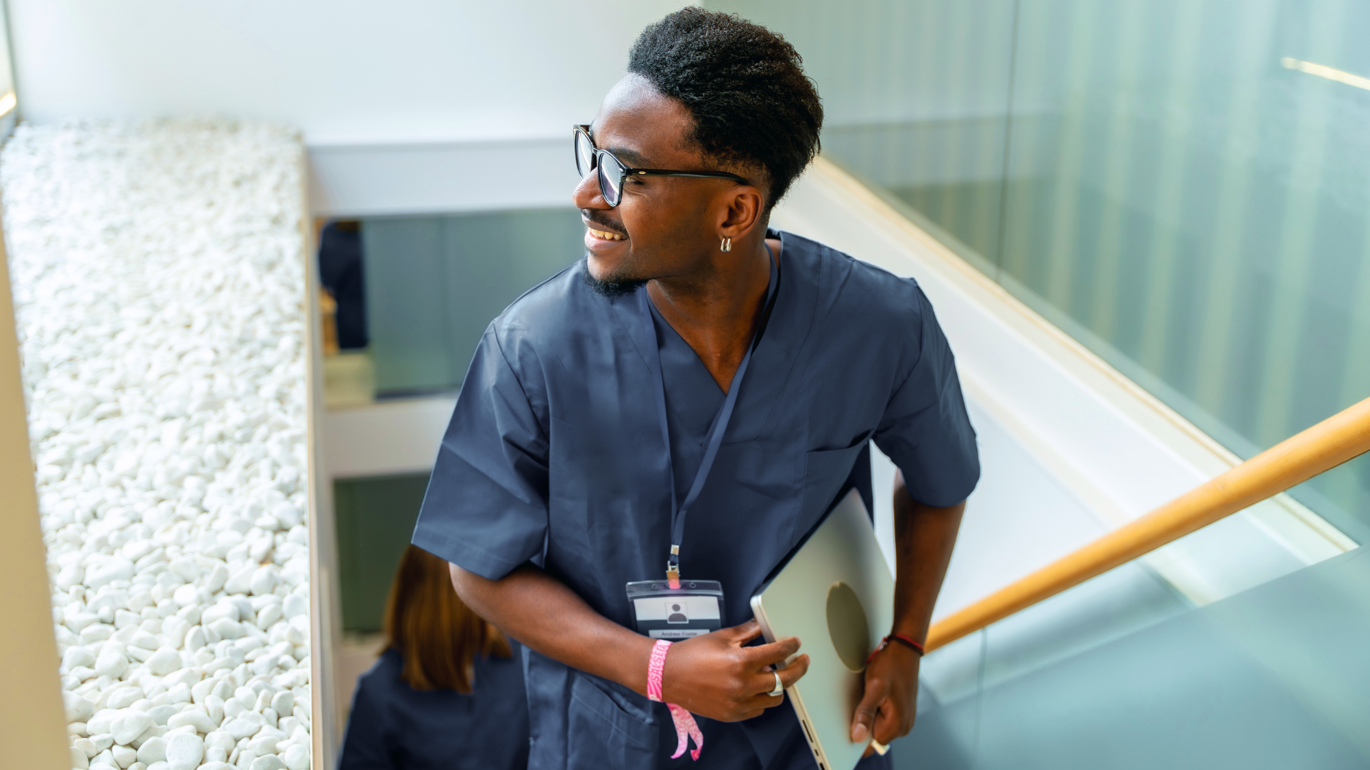 Male telemetry nurse walking up the stairs looking out the window at hospital.