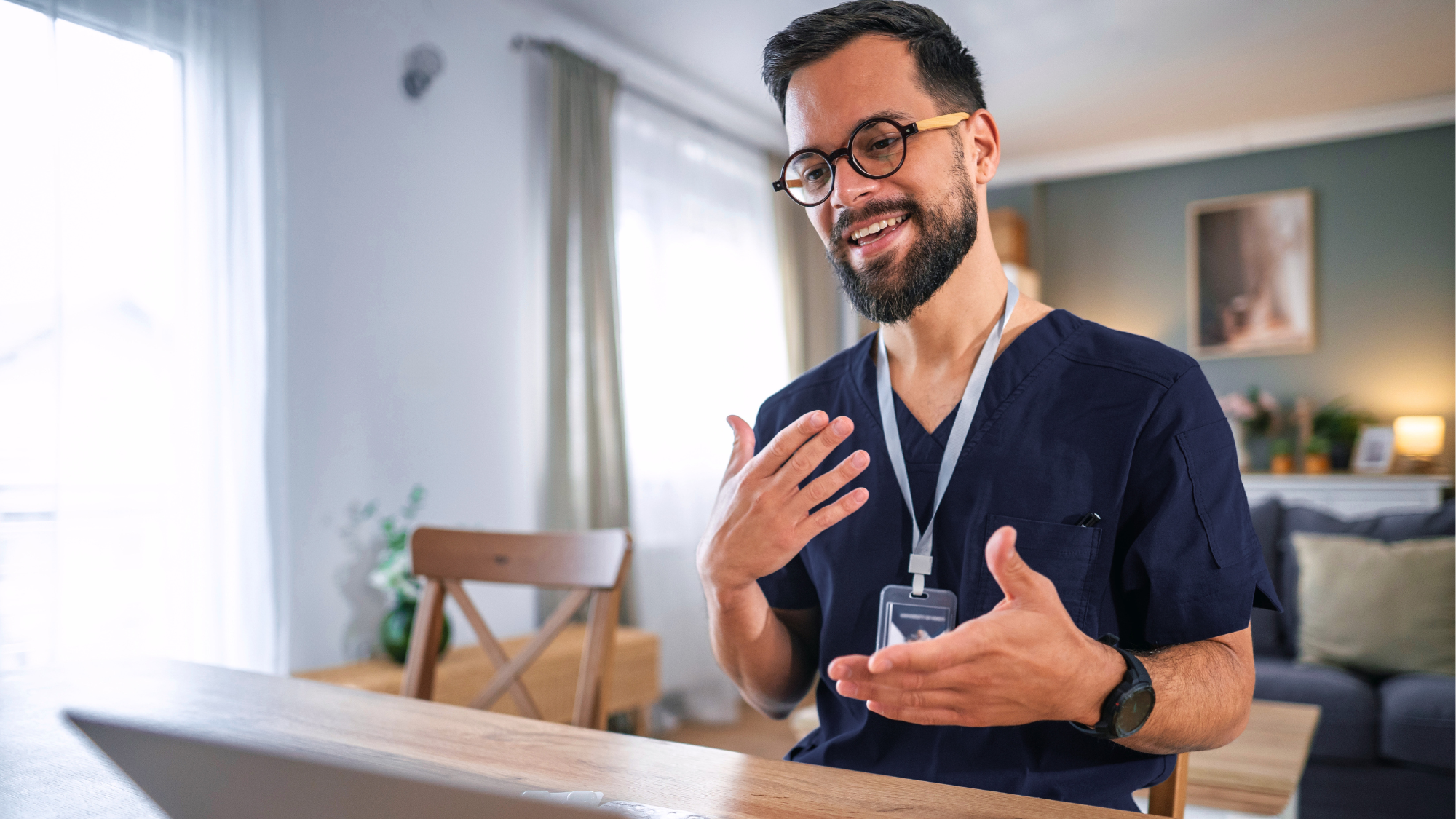 Male travel nurse talking communicating virtually on the computer in a living room.